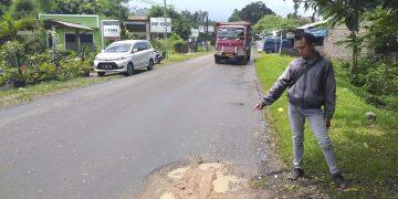 SEORANG WARGA menunjukan jalan berlubang yang kini sudah ditambal, kemarin.*