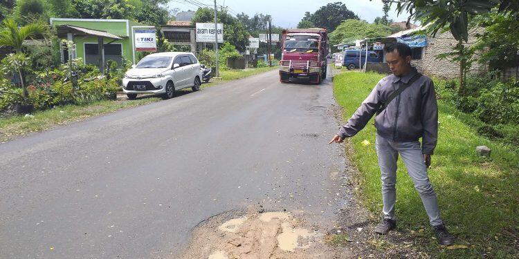 SEORANG WARGA menunjukan jalan berlubang yang kini sudah ditambal, kemarin.*